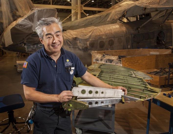 A male museum specialist holds a rubber object he made.