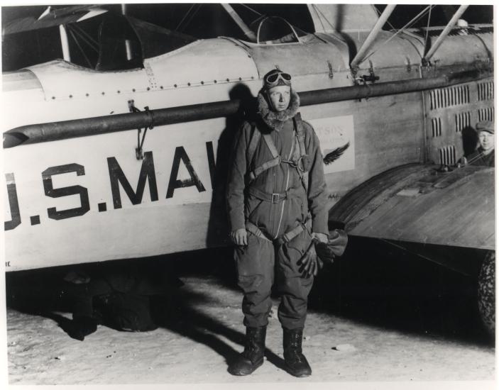 Charles Lindbergh stands in front of an aircraft wearing aviator gear.