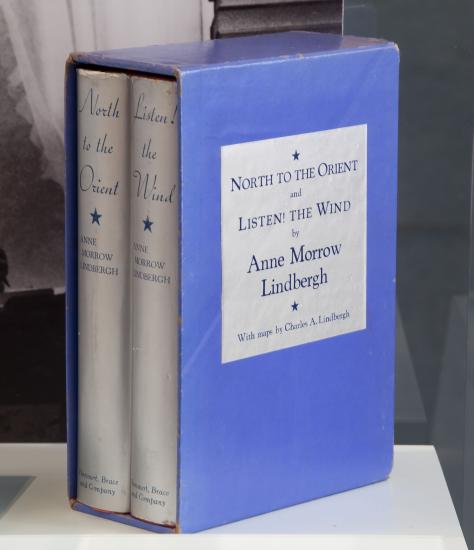 A blue bookcase featuring two books with silver-colored spines written by Anne Morrow Lindburgh about her flights with Charles Lindbergh.