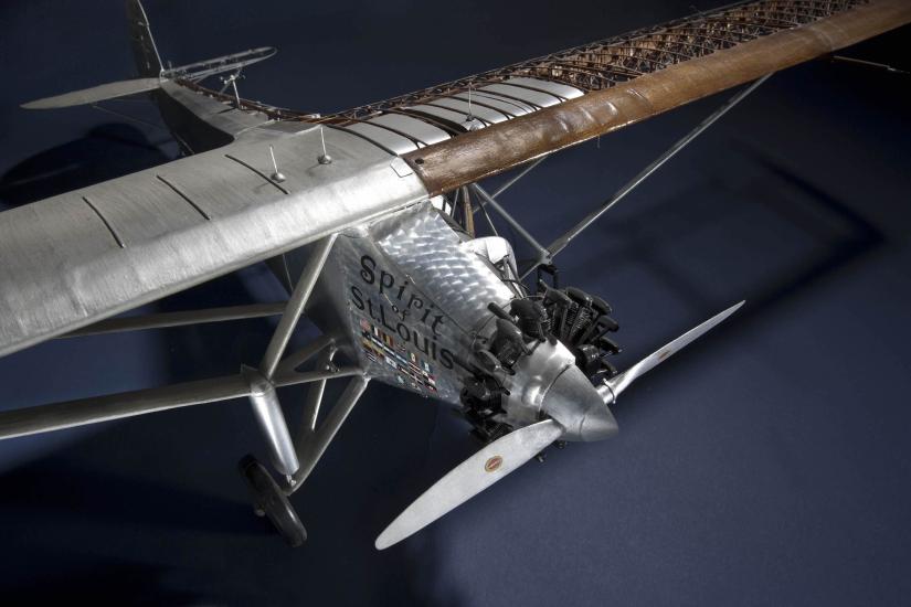 Top view of a cutaway model of the Spirit of St. Louis, a silver-colored monoplane with one engine. This view focuses on the nose and engine of the plane.