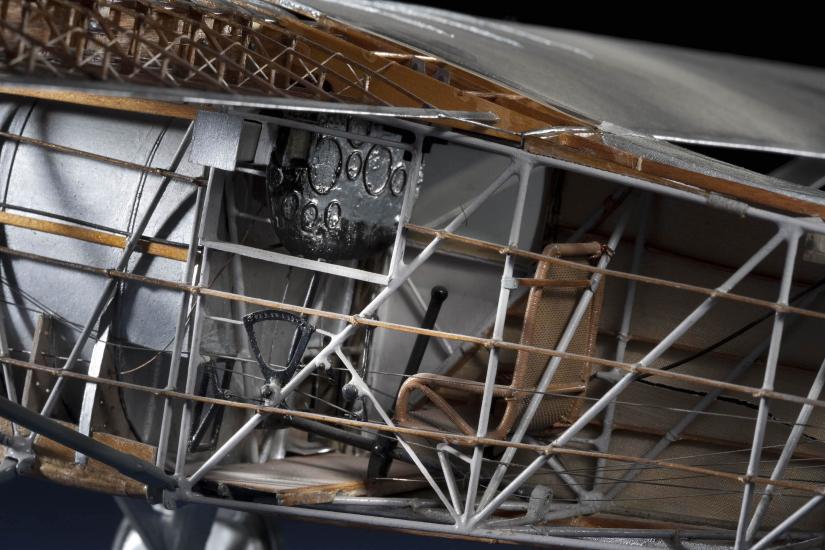 Close-up view of the interior of a cutaway model of the Spirit of St. Louis, a silver-colored monoplane with wooden and metal parts.