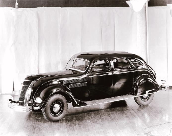 Side view of dark-colored antique car with four seats.