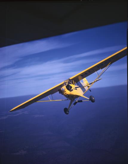 Front view of a yellow monoplane with one engine. The monoplane is in flight.