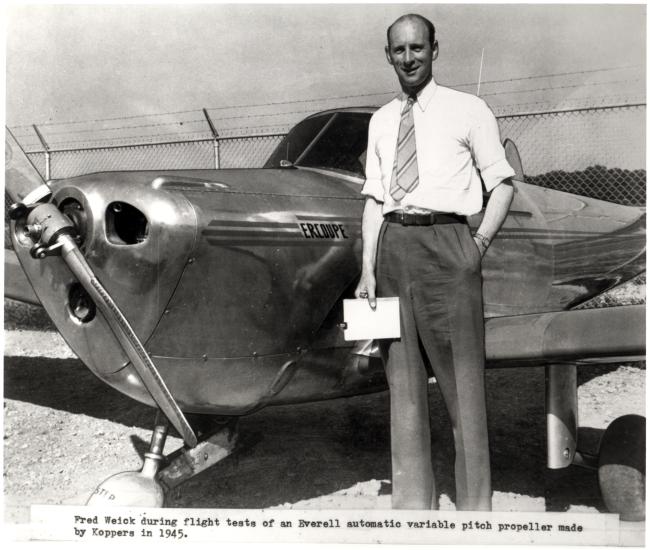 Fred Weick, a white man, stands next to his metal aircraft.