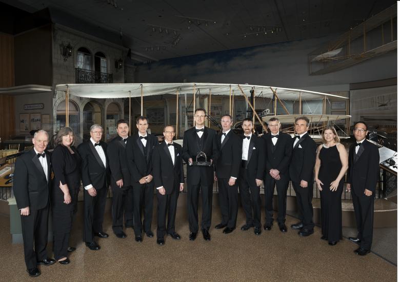 A group of individuals stand together with a trophy at an event hosted by the Museum.