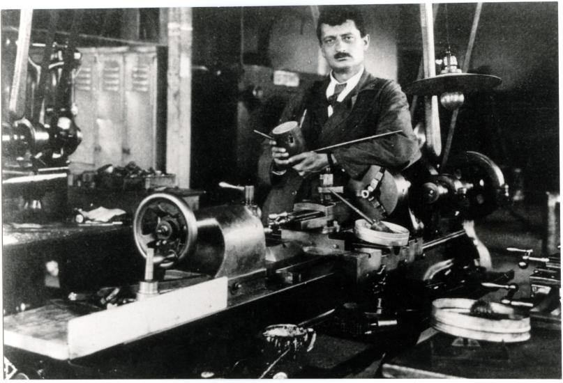 Hermann Julius Oberth, a white man, stands behind a table with primitive rocket parts.