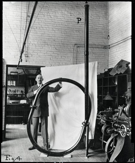 A white man stands while holding a large rounded tube.