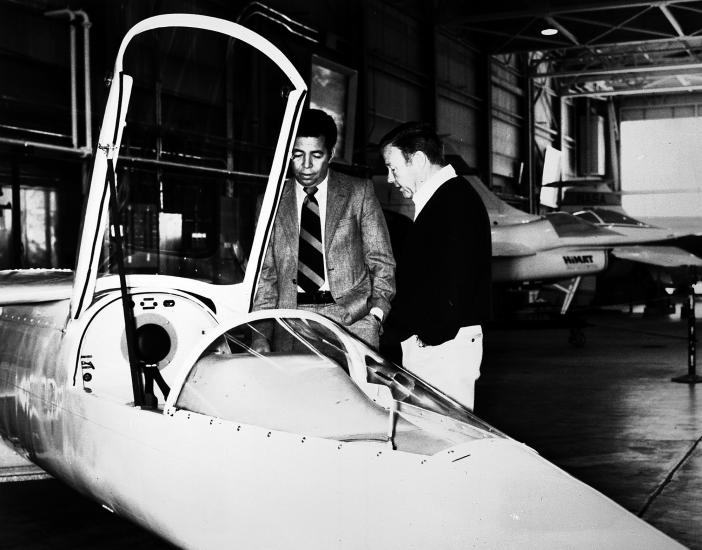 Isaac Gilliam IV, an African-American male, stands next to another man near a white aircraft.