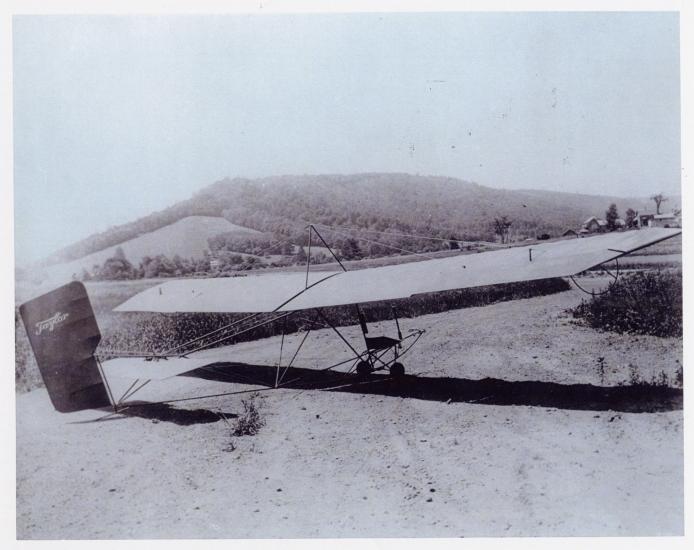 Single-person glider with steel tube frame on ground.