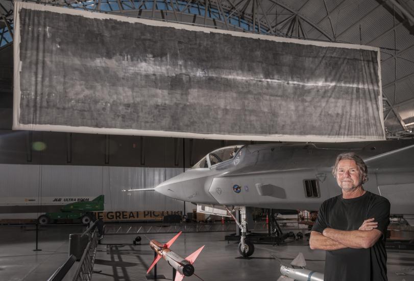 Jacques Garnier, white male co-photographer artist of "The Great Picture", stands in front of the large photo.