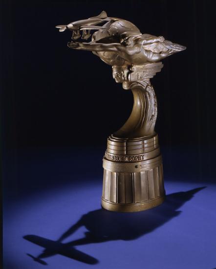 Side view of bronze-colored metal trophy with oblong topper shape.