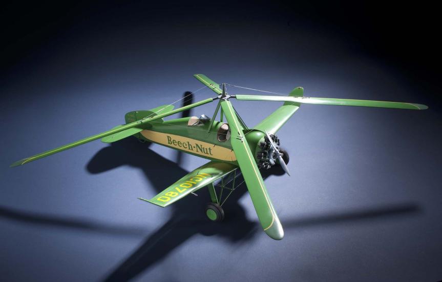 Top view of green and yellow monoplane model with one engine and rotating four-blade propellor above the cockpit. Registration number "NC10780" is painted on the right wing and the name "Beech-Nut" is painted in green.