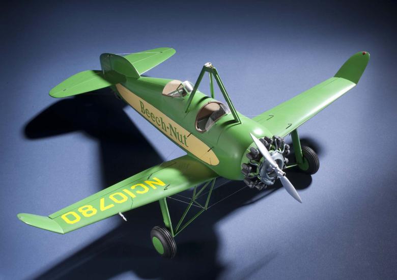 Top view of green and yellow monoplane model with one engine. Registration number "NC10780" is painted on the right wing and the name "Beech-Nut" is painted in green.