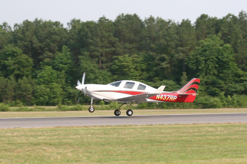 Side view of white and red monoplane with one engine. Monoplane is in takeoff position. Registration number "N437RP" painted in white near tail of plane.