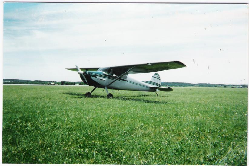 Side view of white and green monoplane with one engine.