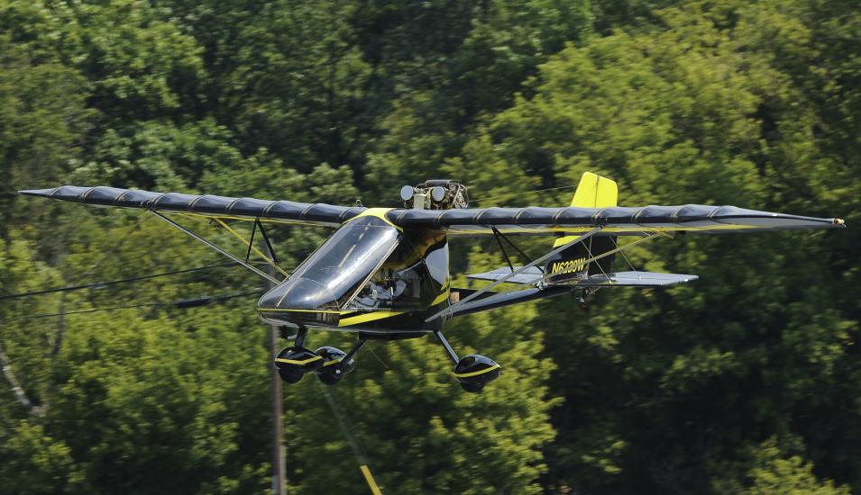 Side view of a black monoplane in flight. Monoplane has fixed landing gear.