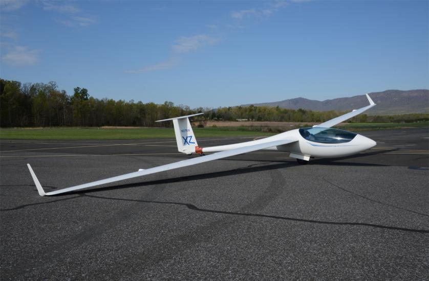 Side view of white glider monoplane with abnormally long wings.