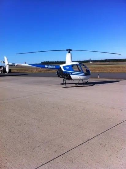 Side view of white and blue helicopter with two propellors at the top. Registration number "N4013R" painted in white on front of tail.