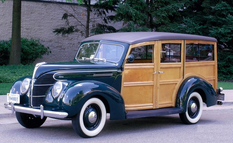 Side view of dark-colored metal, four-door automobile with wooden sides.