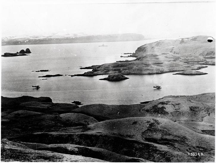 Two aircraft fly directly over a large body of water.