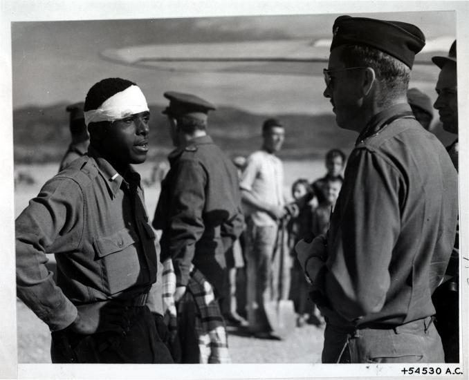 Lt. Andrew D. Mitchell, an African-American male pilot on the left, speaks to another officer following an escape attempt from German territory.