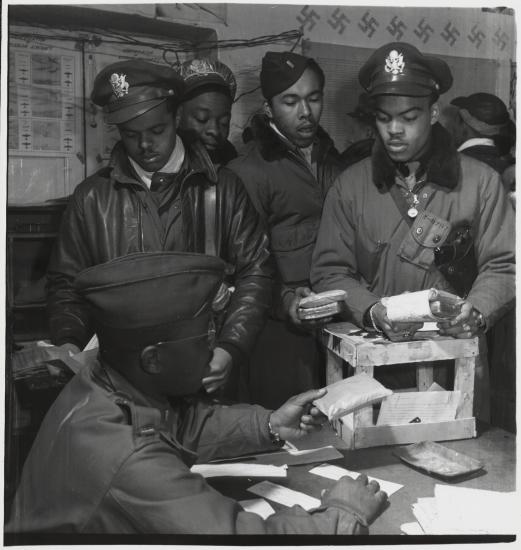 A group of Tuskegee Airmen, who were African-American male pilots during World War II, work on putting escape kits together.