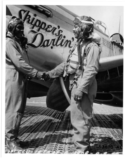 Clarence D. “Lucky” Lester and Andrew D. Turner, both of whom are African-American male pilots, shake each other's hand in front of an aircraft.