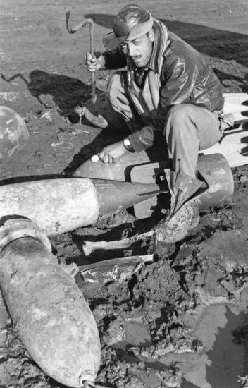 Lt. Elwood T. Driver, an African-American male pilot, sits and poses informally on top of rocket debris.