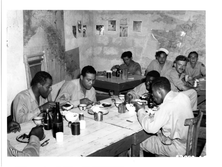 Joe Louis, an African-American boxer, dines with African-American Tuskegee Airmen.