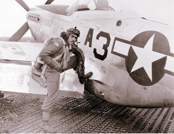 Lt. Edward M. Thomas, an African-American Tuskegee Airman, sits on the wing of an aircraft.