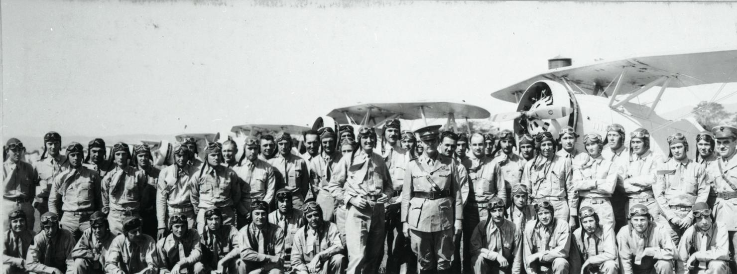 A large group of Marine Corps pilots in the early 1930s stand together outdoors for a portrait.