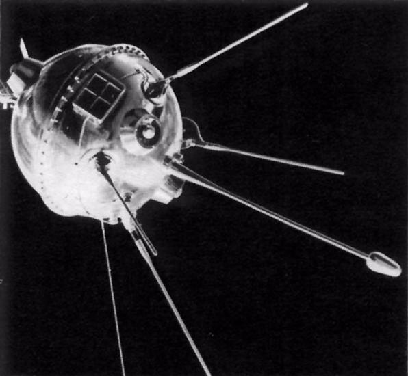 View of metal orbiting sphere-like base of an object with multiple antenna probes attached to bottom of base object. A square attachement featuring smaller square panels is attached above the antennae probes.