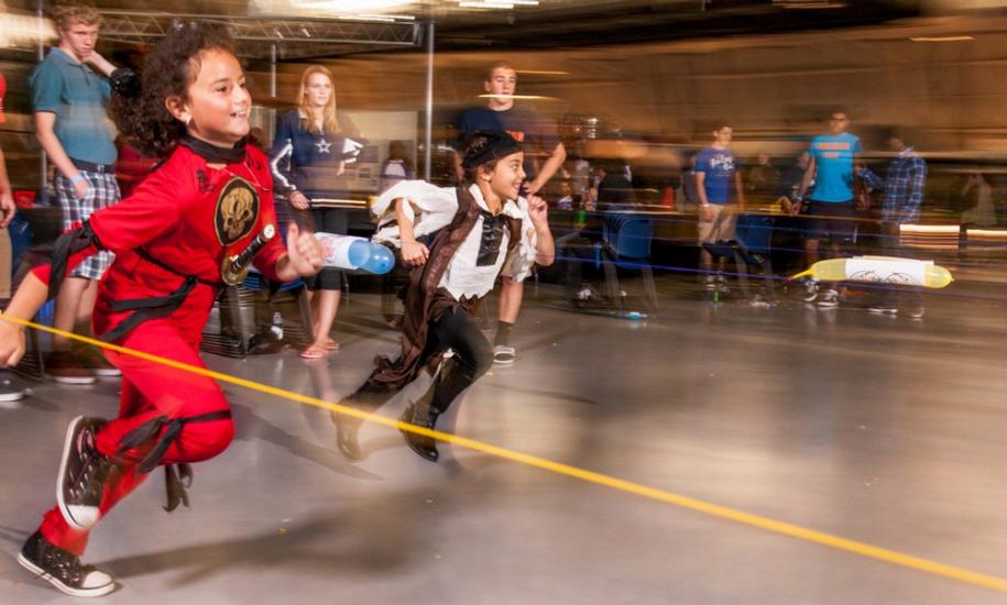 Two kids wearing Halloween costumes participate in a rocket activity during a Halloween event at the Museum.