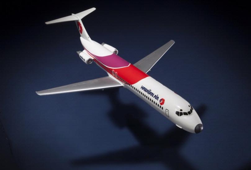 Top view of resin commercial aircraft model with white, red, and purple livery. Hawaiian Air is painted toward the front of the fuselage.