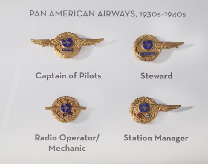 A set of four badges used by Pan American Airways during the 1930s and 1940s. Each badge features a dark blue circle surrounded by a golden circle. The golden circle usually features a small emblem highlighting each job position.