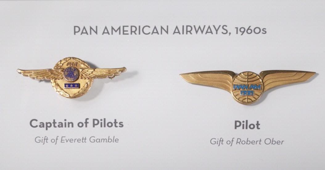 Set of two badges given to the captain of pilots, on the left, and a pilot, on the right, of Pan American Airways in the 1960s. The badges both are gold-colored and have a circle shape surrounded by stylized wings.