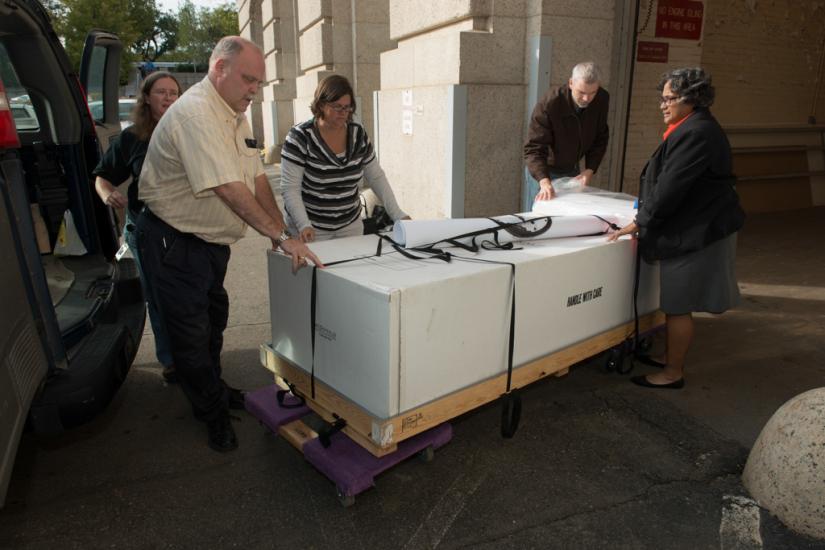 Five Museum staff members transport Neil Armstrong's spacesuit outside into another Smithsonian museum building.