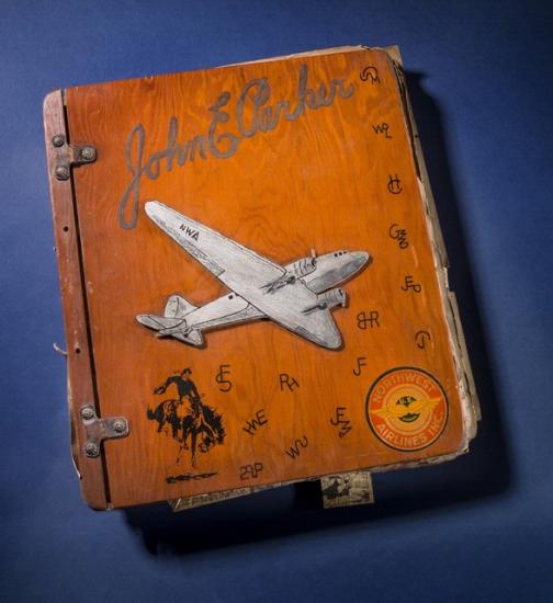 Wooden-colored scrapbook cover featuring a white aircraft. The scrapbook owner's name is written in cursive above the aircraft.