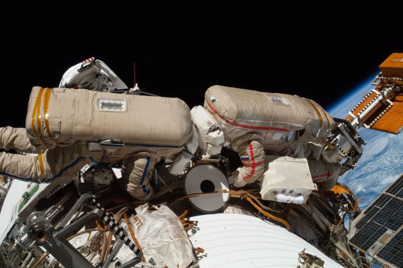 Two Russian Cosmonauts, both wearing spacesuits, work outside of the International Space Station during a spacewalk.