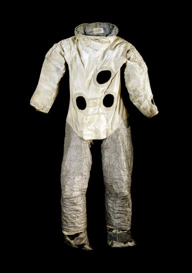 Front view of astronaut suit used for astronaut training on Earth. The top half features a white fabric with multiple holes representing life support tubes, whereas the bottom half features a silver-colored fabric.