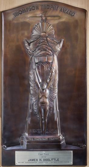 Wooden plaque featuring the "Thompson Trophy Award" name above a depiction of a male angel below a sky landscape. A silver-colored metal part enscribes James H. Doolittle as the recipient of the trophy in 1932.