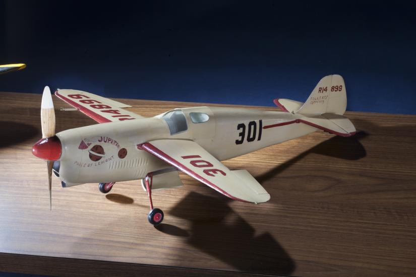 Side view of white monoplane model with one engine. The number 301 is painted in black on the rear of the fuselage and in red on the left wing.