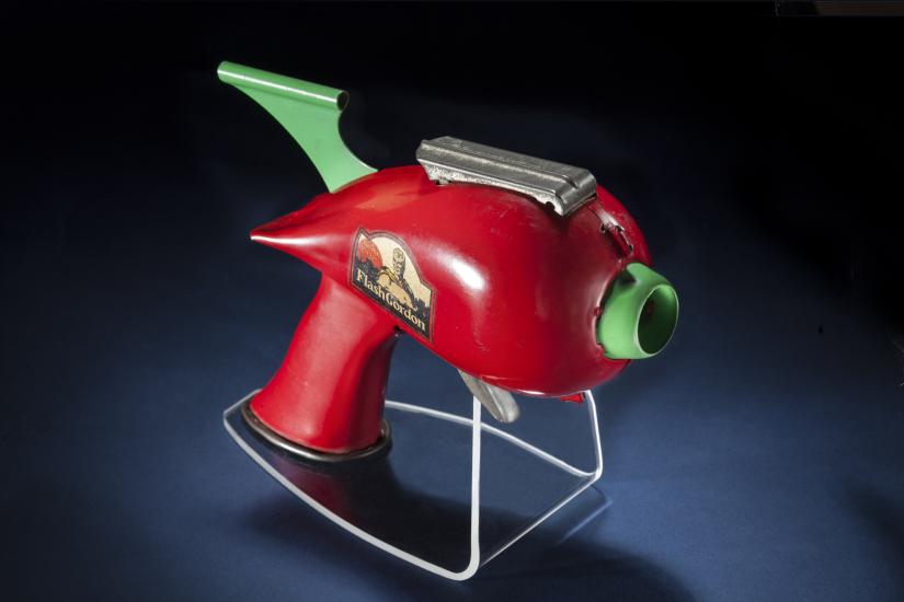 Side view of red-colored steel gun toy with light green trigger.