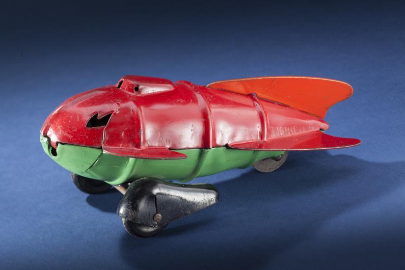 Side view of red and light green teardrop-shaped rocket ship. 