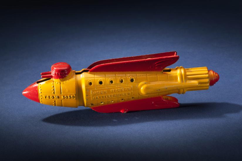 Side view of yellow rocket with red fins and nose.