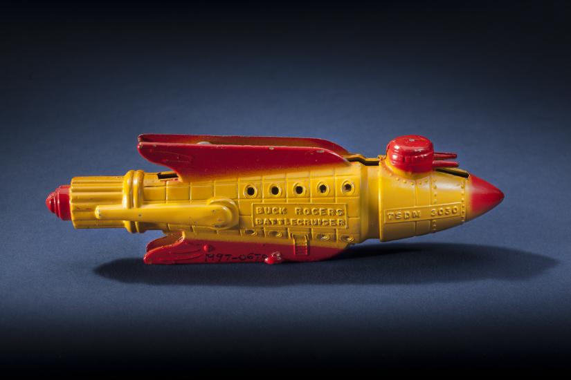 Side view of yellow rocket with red fins and nose.