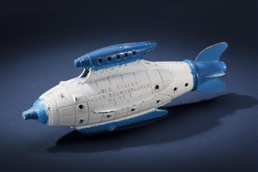 Side view of white torpedo-shaped destroyer toy with blue propellor, nose, and fins.