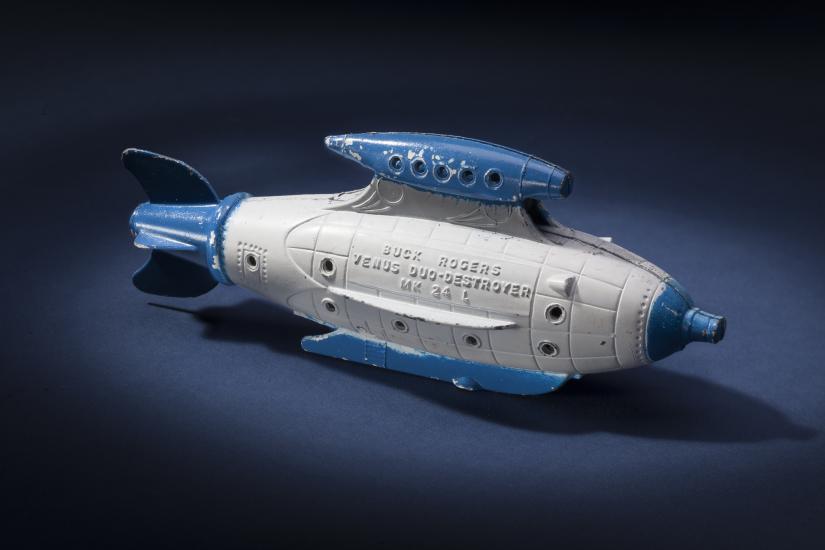 Side view of white torpedo-shaped destroyer toy with blue propellor, nose, and fins.