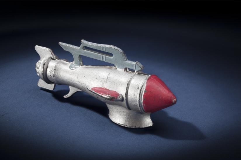 Side view of silver-colored metal missile-shaped spaceship with red nose.