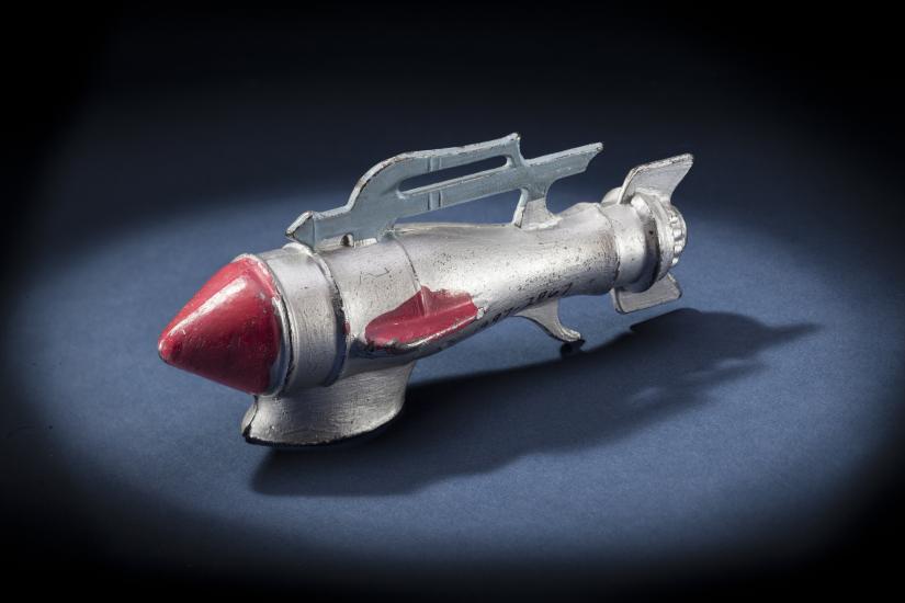 Side view of silver-colored metal missile-shaped spaceship with red nose.